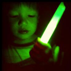 Boy playing with a glow stick, which uses bioluminescence to work.