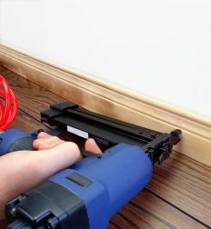 Brad nailer being used to secure baseboard to a wall