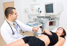 A sonographer moving an ultrasound transducer over a woman's stomach.