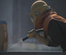 A person sandblasting using silica sand.