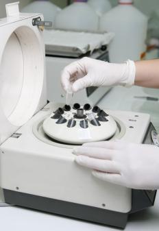 A microbiology technician placing a test tube in a centrifuge