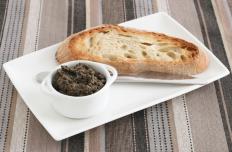Tapenade in a ramekin, served with a slice of bread.
