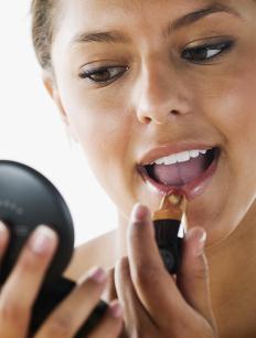 A woman applying lipstick to enhance her natural beauty.