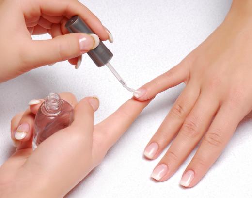 A nail technician polishing a woman's fingernails in a salon.