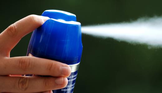 A person using bug spray to prevent ticks.