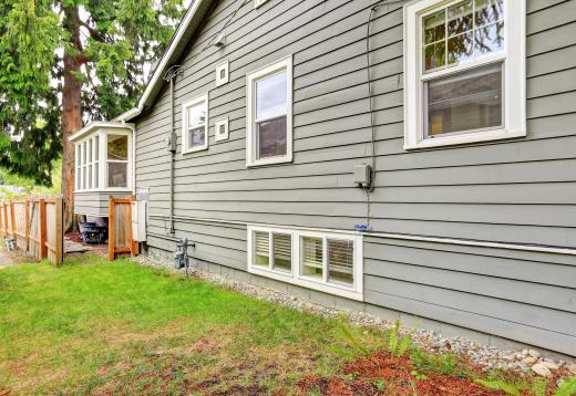 Fiber cement siding boards are fastened to walls in overlapping rows in the style of clapboard siding.