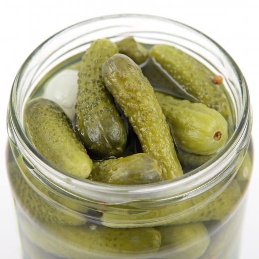 A canning jar of pickled gherkins. The label on a jar should include the food name and the date it was canned.