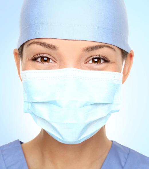 A scrub nurse typically wears a sterile cap and mask while assisting doctors in an operating room.