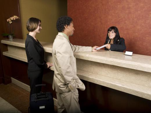 A hotel receptionists checks guests into a hotel.