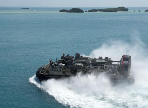 The specific manuevrers used to land several hovercraft on a hostile beach are tactics, while the decision to conduct an amphibious landing would be part of a strategy.