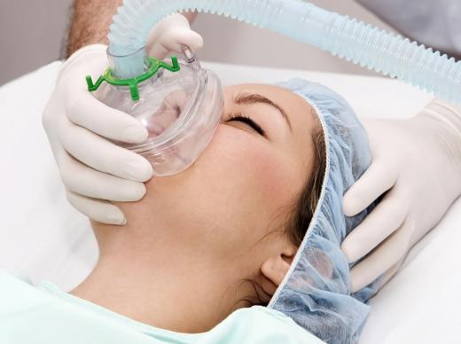 A nurse anesthetist administers anesthesia during surgery.