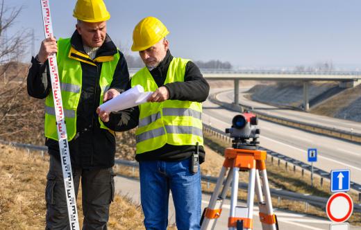 A quantity surveyor trainee assists the main quantity surveyor at a construction job site or office position.