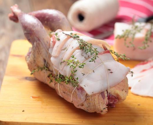 Whole chickens can be stuffed and trussed with twine and herbs before baking.