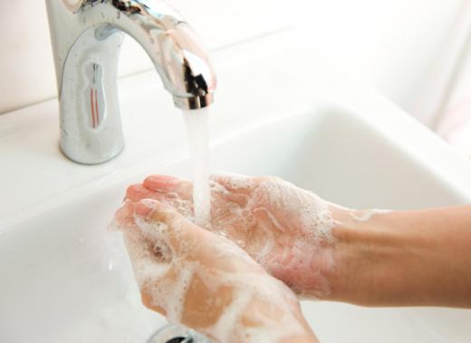 A person washing his hands in water from a bathroom faucet.